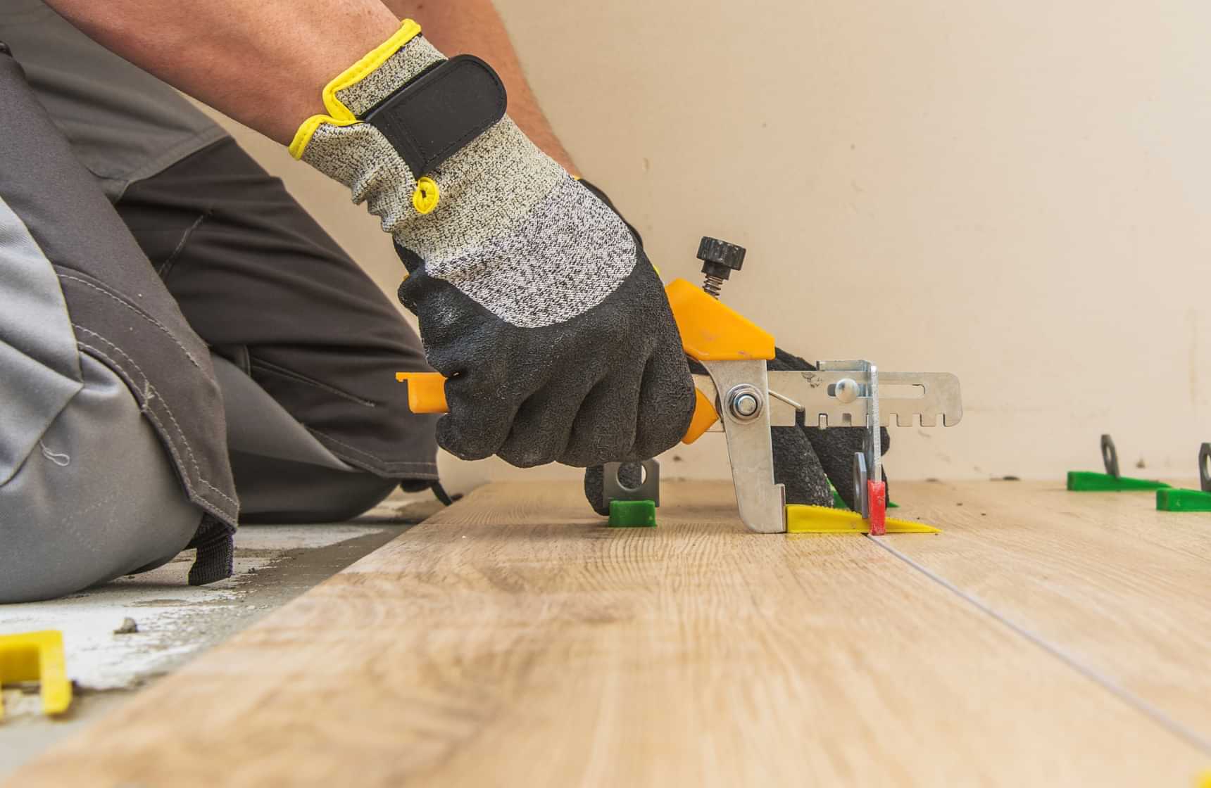 Technician installing wood-look flooring with a flooring installation tool
