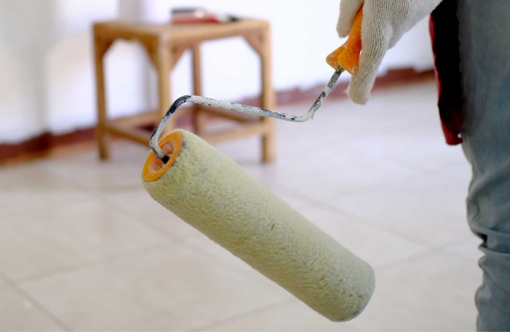 Painter holding a paint roller while preparing to paint an interior wall