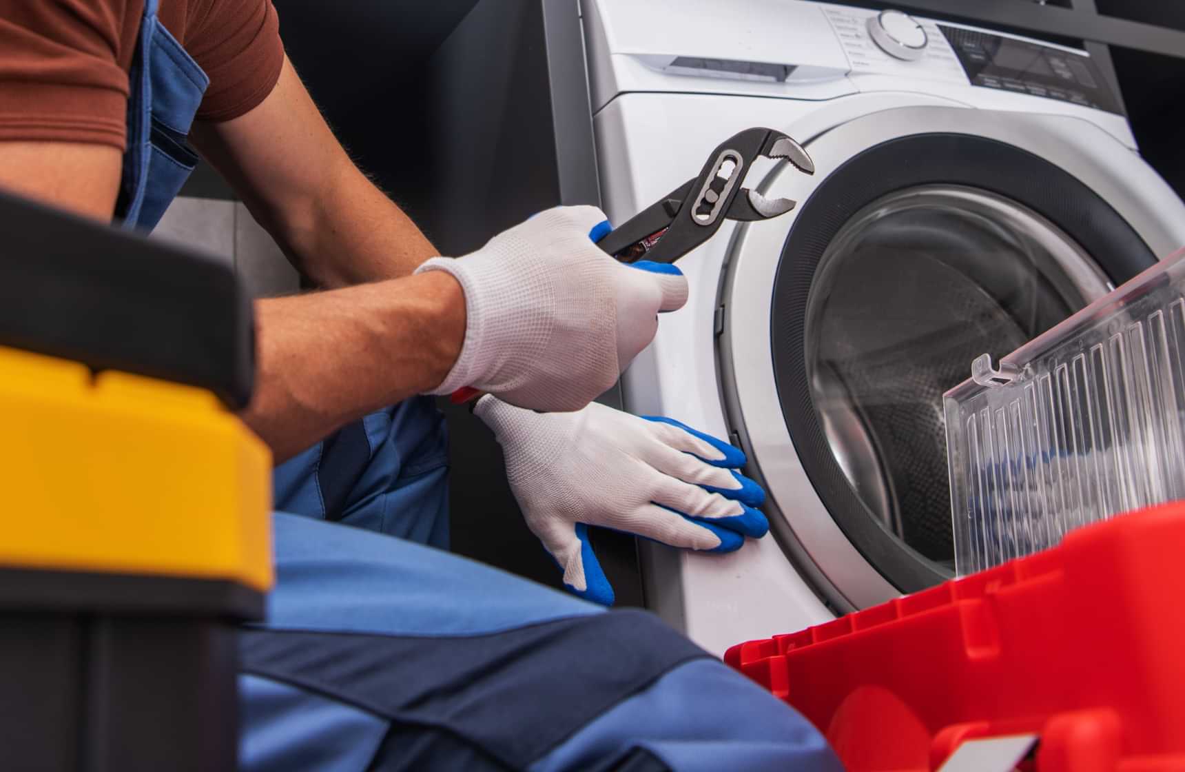 Appliance repair technician inspecting a washing machine door with pliers