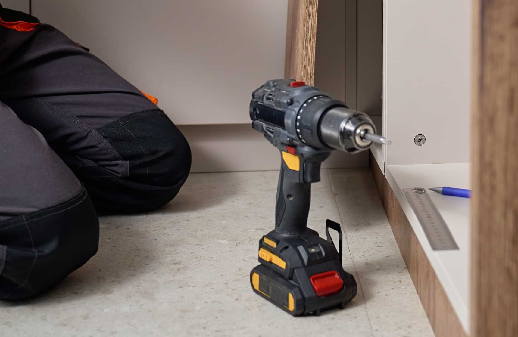 Technician installing cabinet hardware with a cordless drill