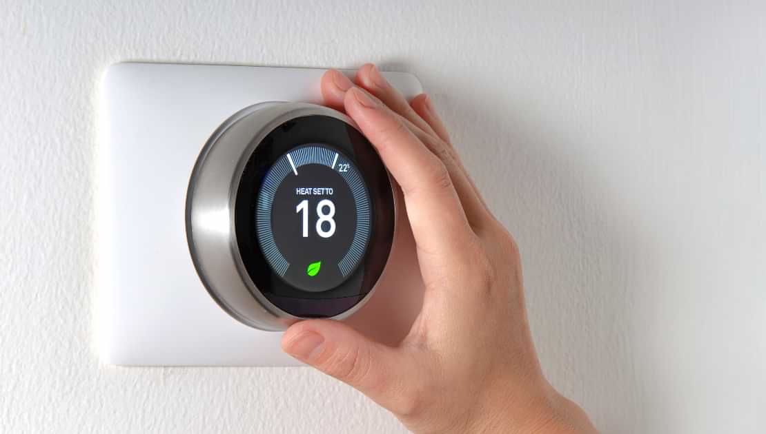 Hand adjusting a smart thermostat for home air conditioning