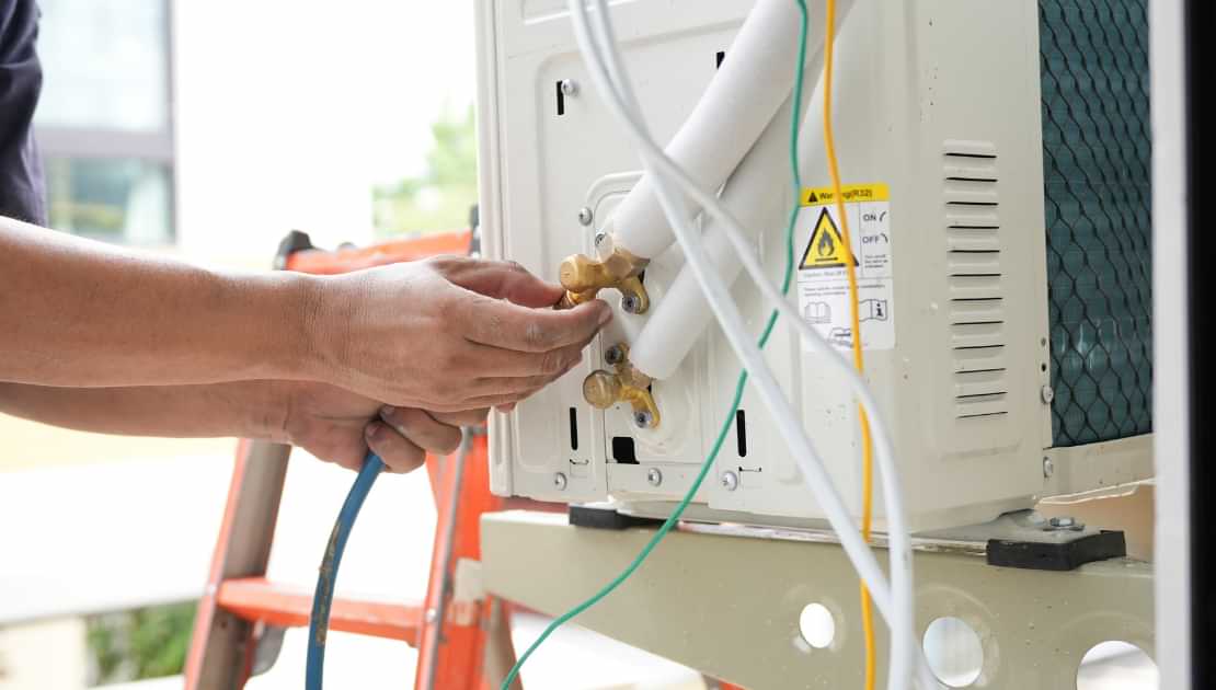 Technician servicing outdoor air conditioning unit during AC maintenance