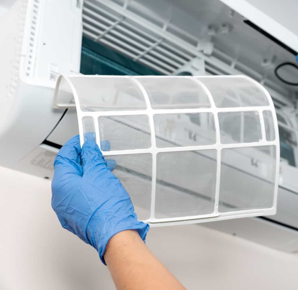 Technician removing and cleaning an air conditioner filter