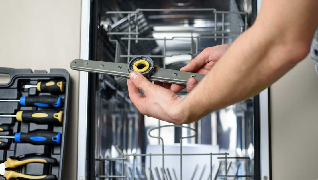 Dishwasher spray arm being inspected during appliance repair