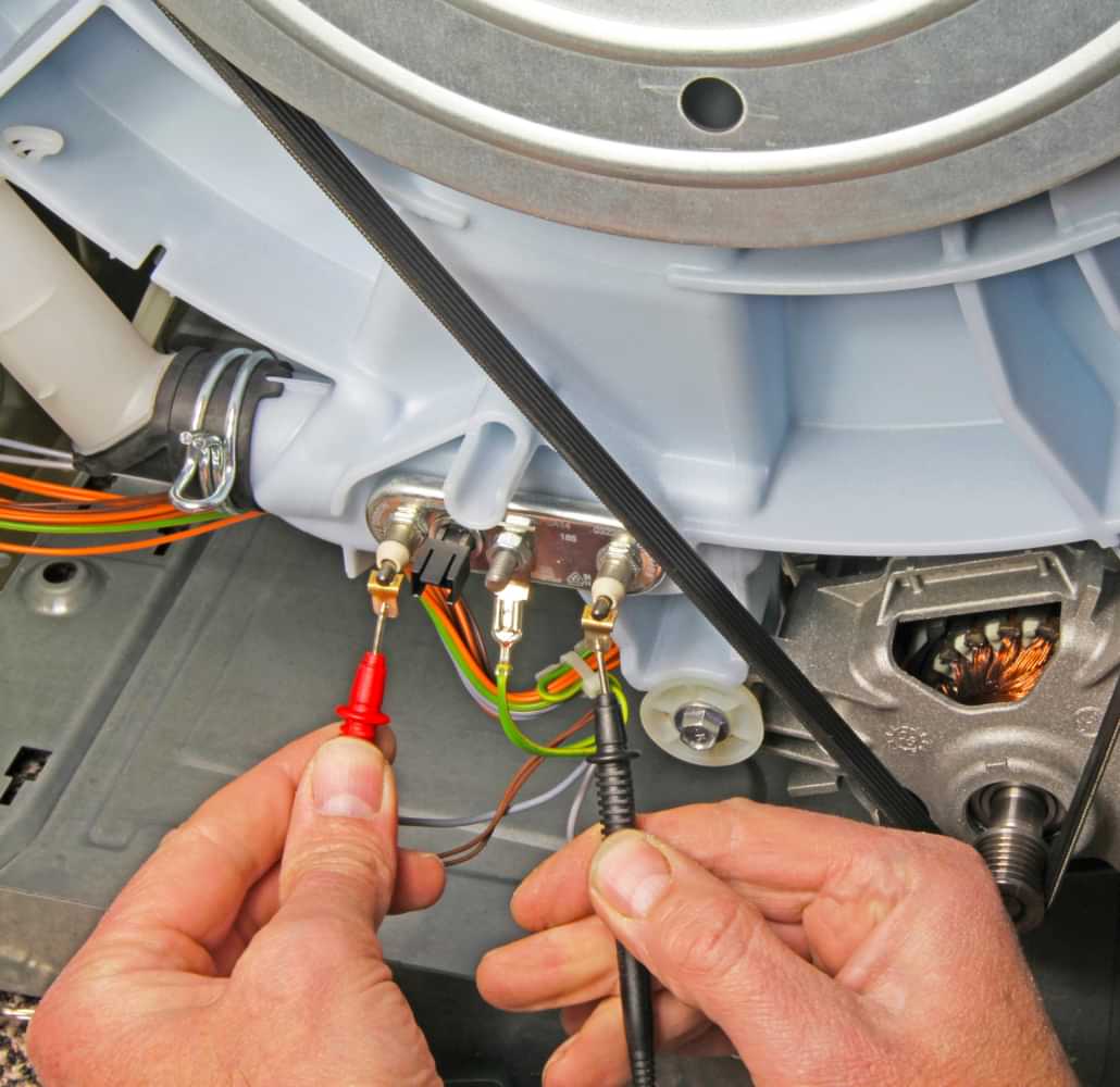 Technician testing washing machine wiring during appliance repair