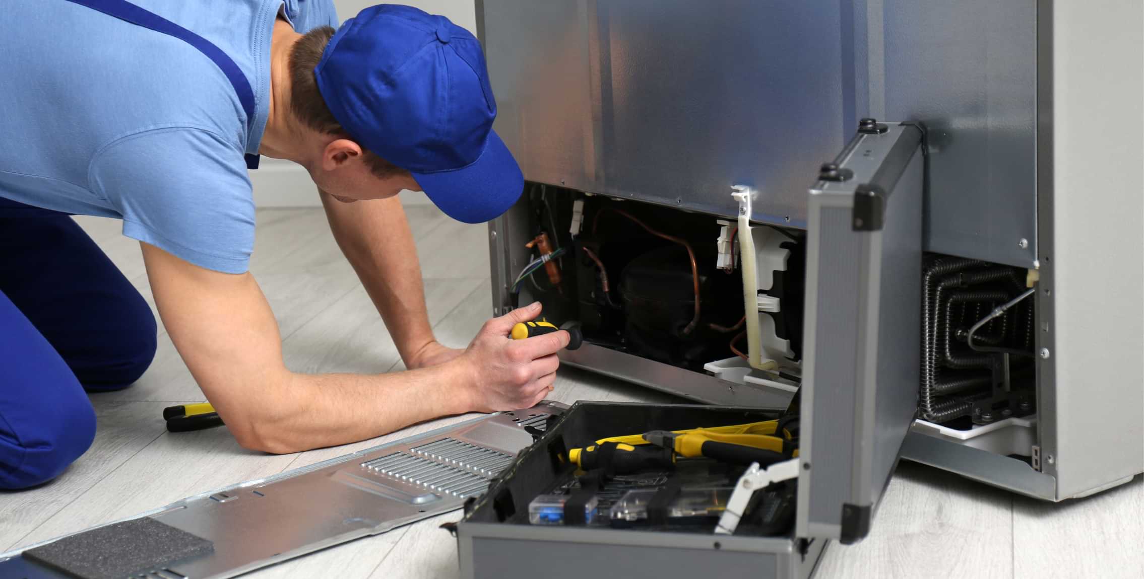Technician repairing a household appliance with tool kit nearby