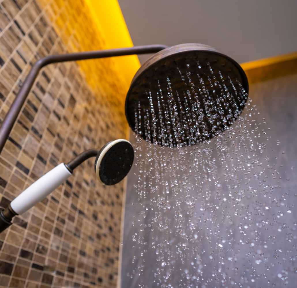 Shower head running water in a bathroom