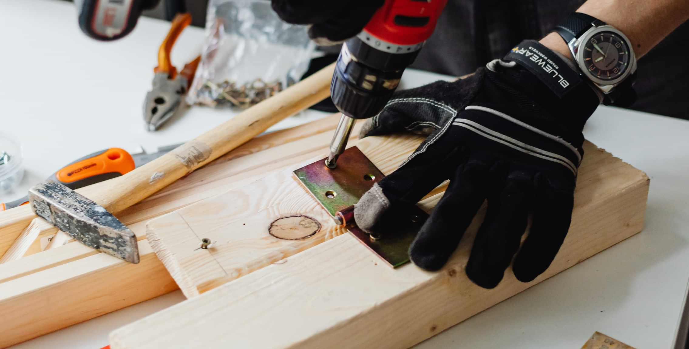 Carpenter drilling a metal bracket into a wooden board