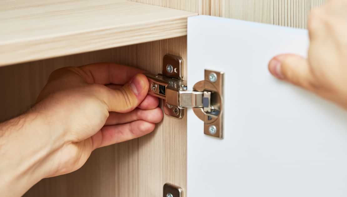 Cabinet hinge being adjusted during carpentry repair work