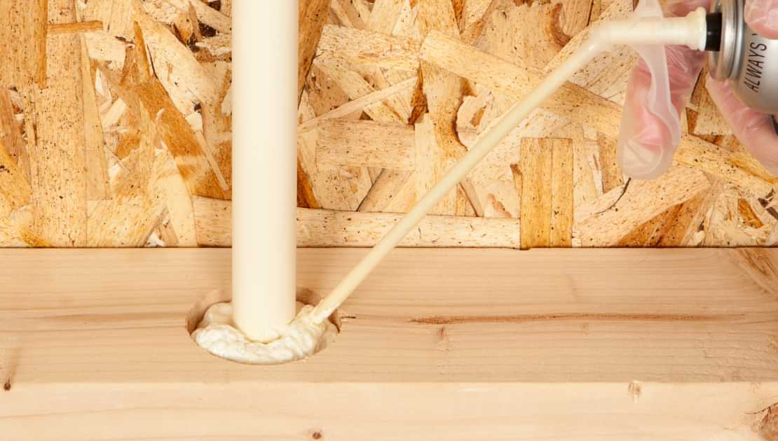 Expanding foam sealant applied around a pipe for weatherproofing