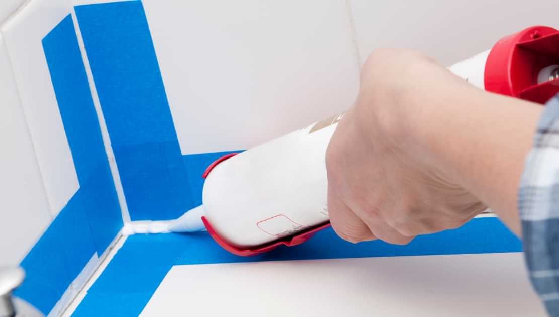 Caulk being applied along a taped corner seam for a clean waterproof finish