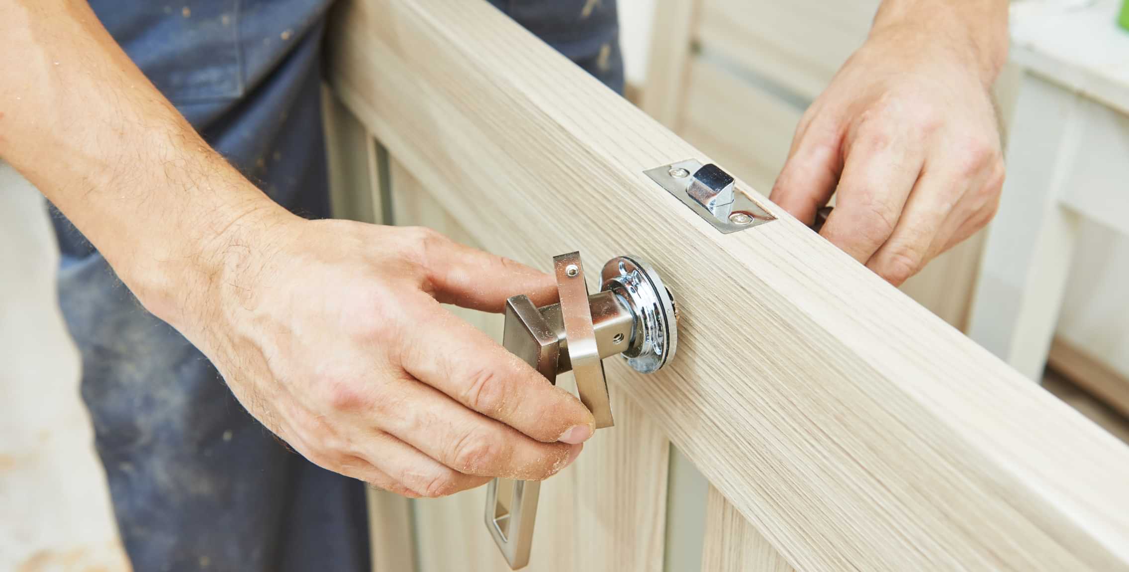 Technician installing a door handle and lock hardware on a wooden interior door