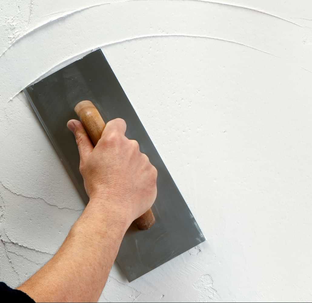Hand smoothing plaster on a wall with a trowel