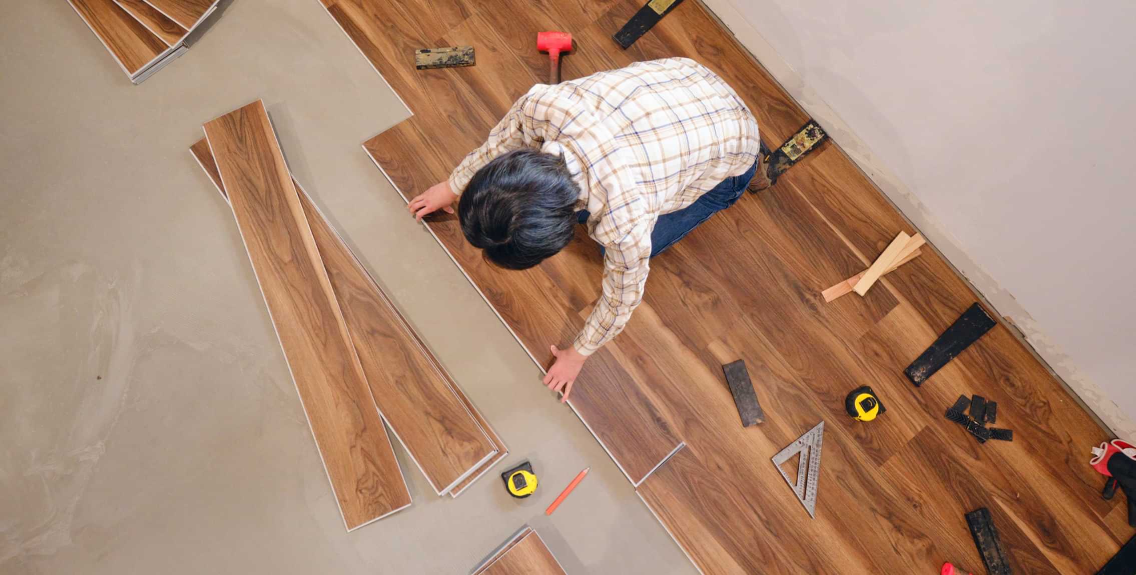 Laminate flooring installation in progress with installer laying wood-effect floor planks