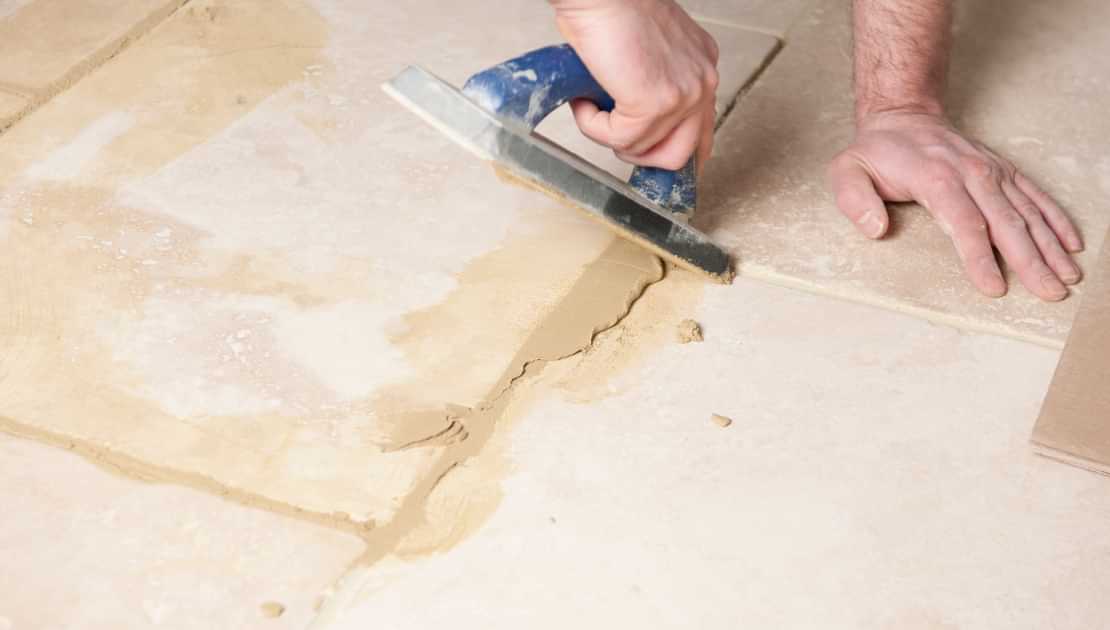 Applying adhesive with a trowel during tile floor installation