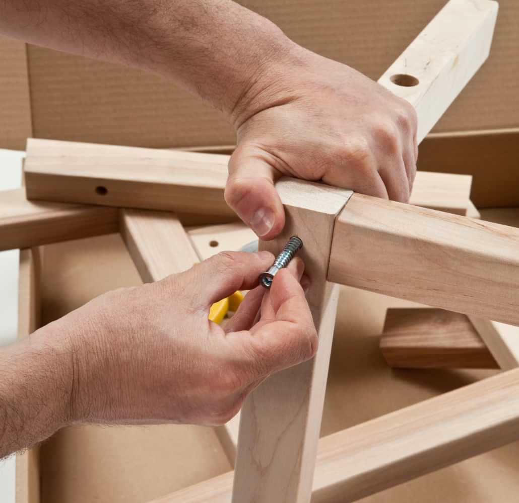 Hands assembling wooden furniture with screws
