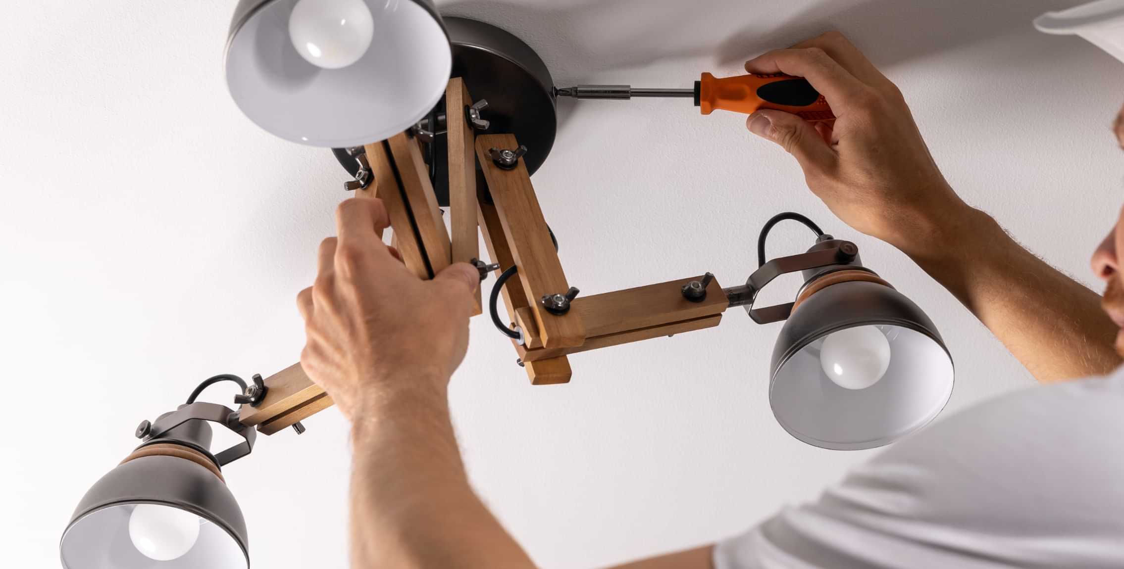 Installing a ceiling light fixture with a screwdriver during minor electrical repairs