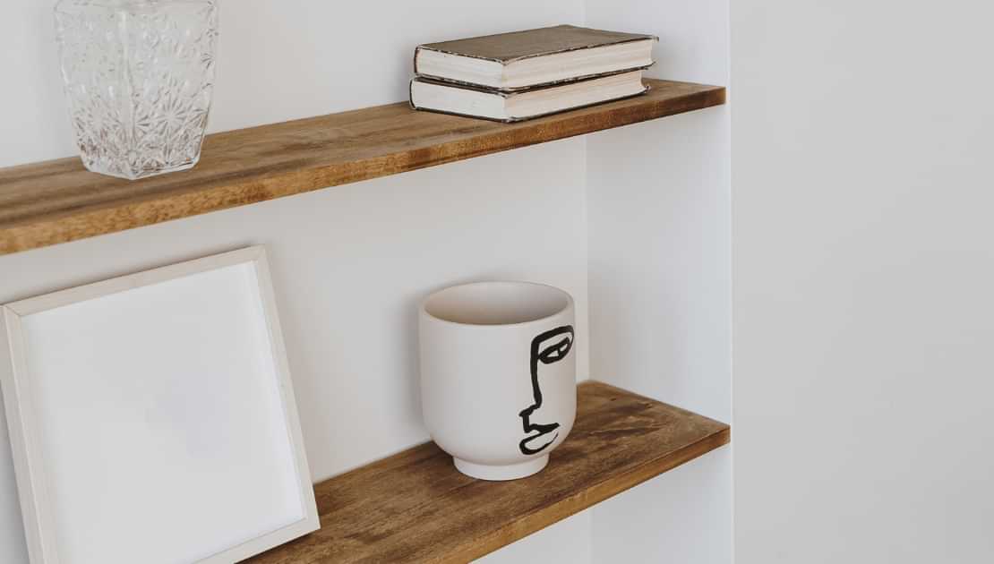 Floating wooden shelves mounted on a white wall with home decor