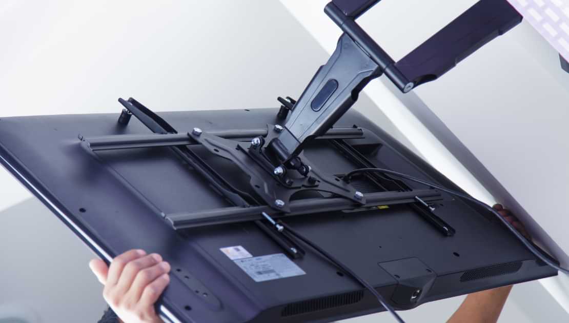 TV being installed on an adjustable wall mount bracket
