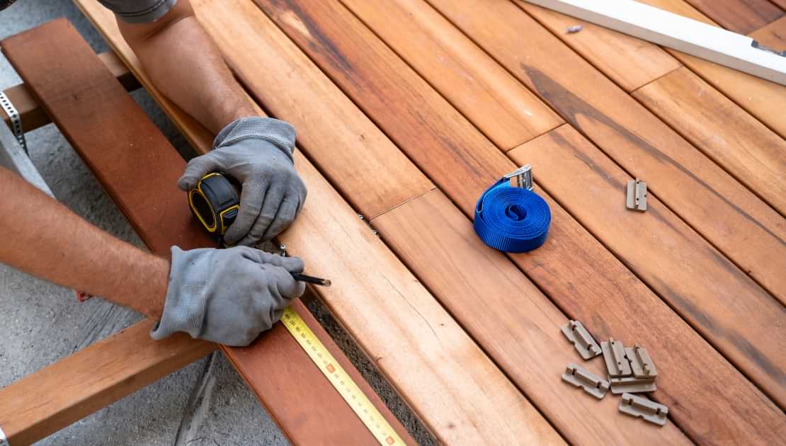 a patio area Measuring and marking wooden decking boards during outdoor deck repair