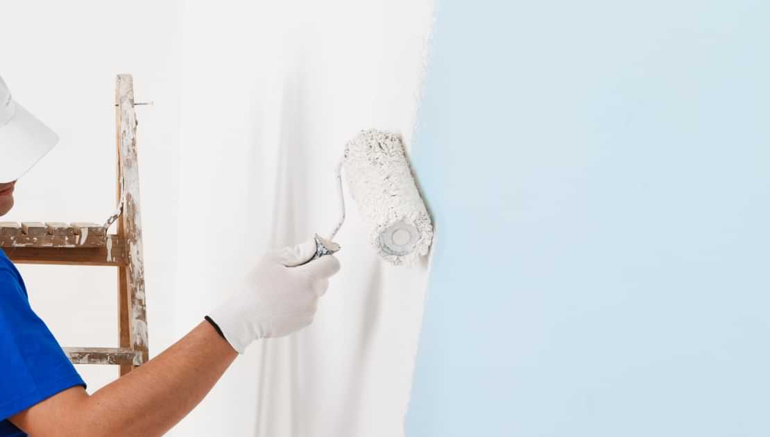 Painting an interior wall with white paint over a light blue surface