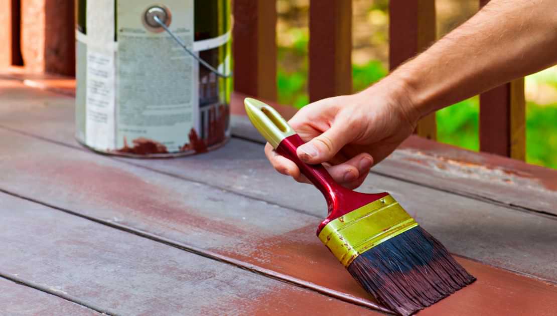 Applying wood stain or exterior paint to outdoor decking with a brush