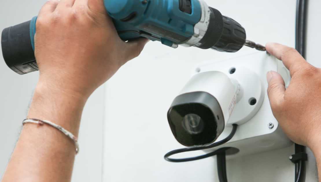 Mounting a security camera with a power drill during property maintenance